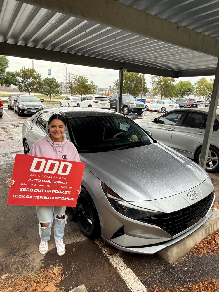 Customer holding a DDD sign next to a repaired silver Hyundai Elantra